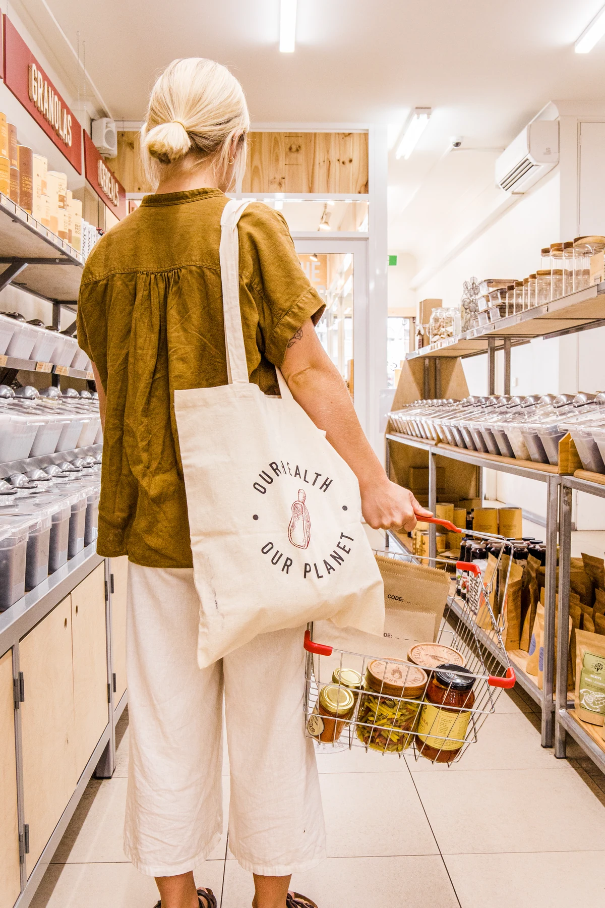 A customer exploring a Scoop store with a reusable bag and shopping basket