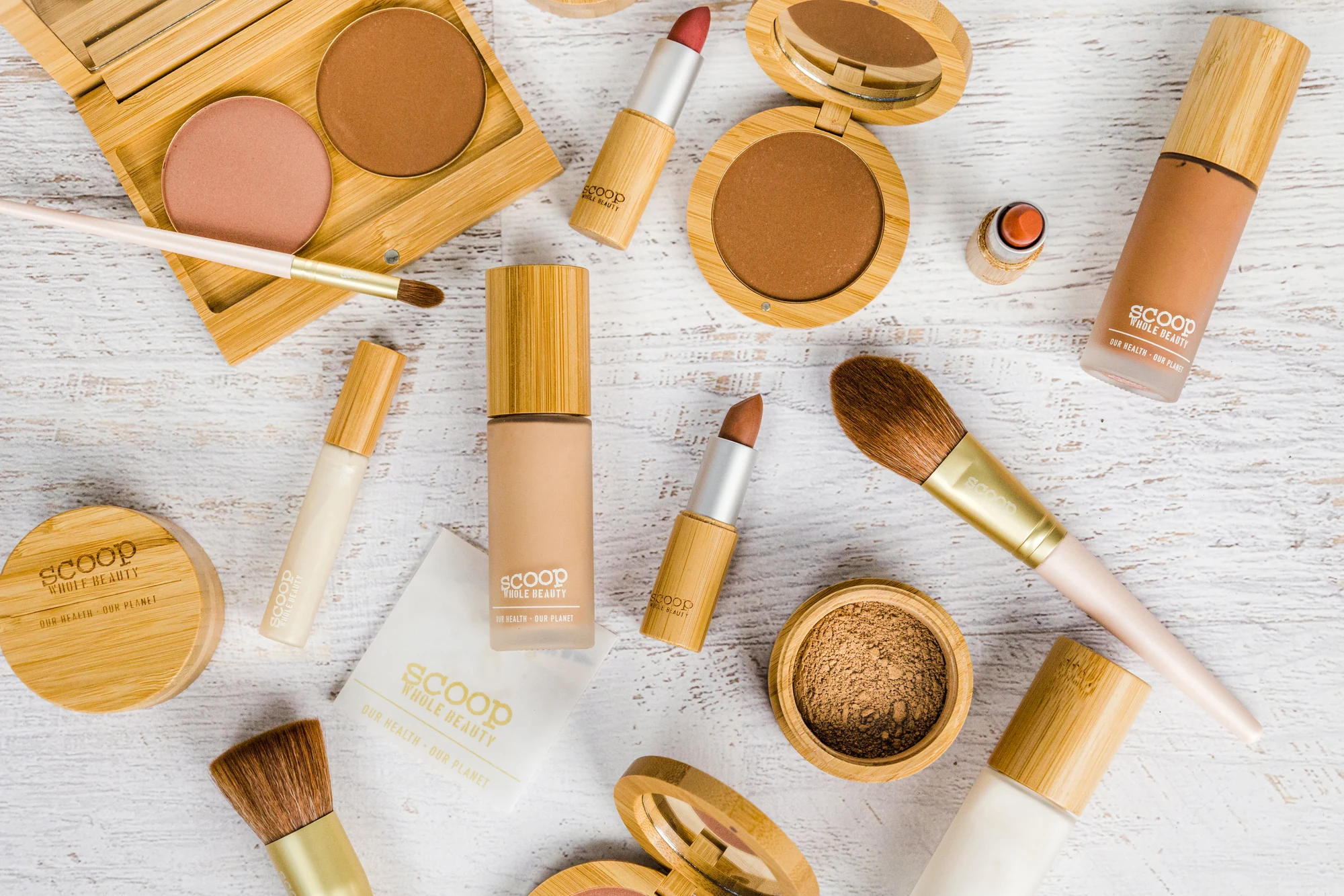 Scoop Whole Beauty refillable makeup in bamboo packaging on a light timber surface